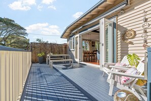 A deck with a dining area, a covered seating area, and a view of the interior. - Coastal Retreat close to Devonport Beaches (Auckland)