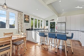 Een moderne keuken met een groot eiland, witte kasten en een eethoek met houten meubels.