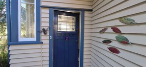 A house with a blue door, a number '2' on the door, and a window with a decorative insect.