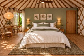 Ein gemütliches Schlafzimmer mit Bett, Nachttischen, einem Sessel, einem Tisch und einem Fenster mit Vorhängen.