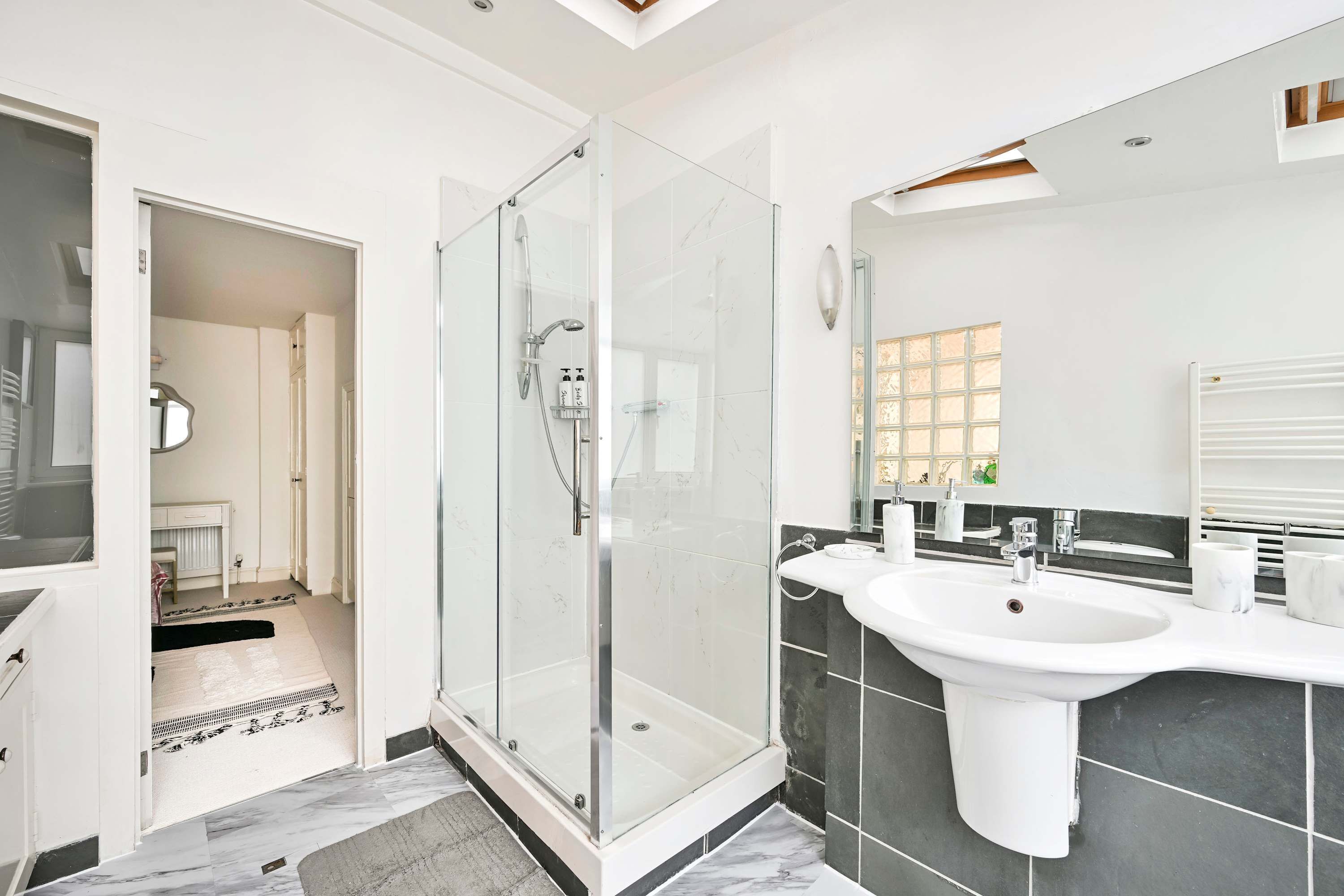 A modern bathroom with a glass-enclosed shower, a large sink, and a mirror.