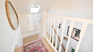 A staircase with white railings, a mirror, a patterned rug, and a ceiling fan. - Chelsea Loft - Stylish Sanctuary (London)