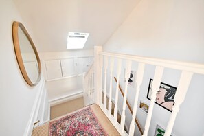 A staircase with white railings, a mirror, a patterned rug, and a ceiling fan. - Chelsea Loft - Stylish Sanctuary (London)