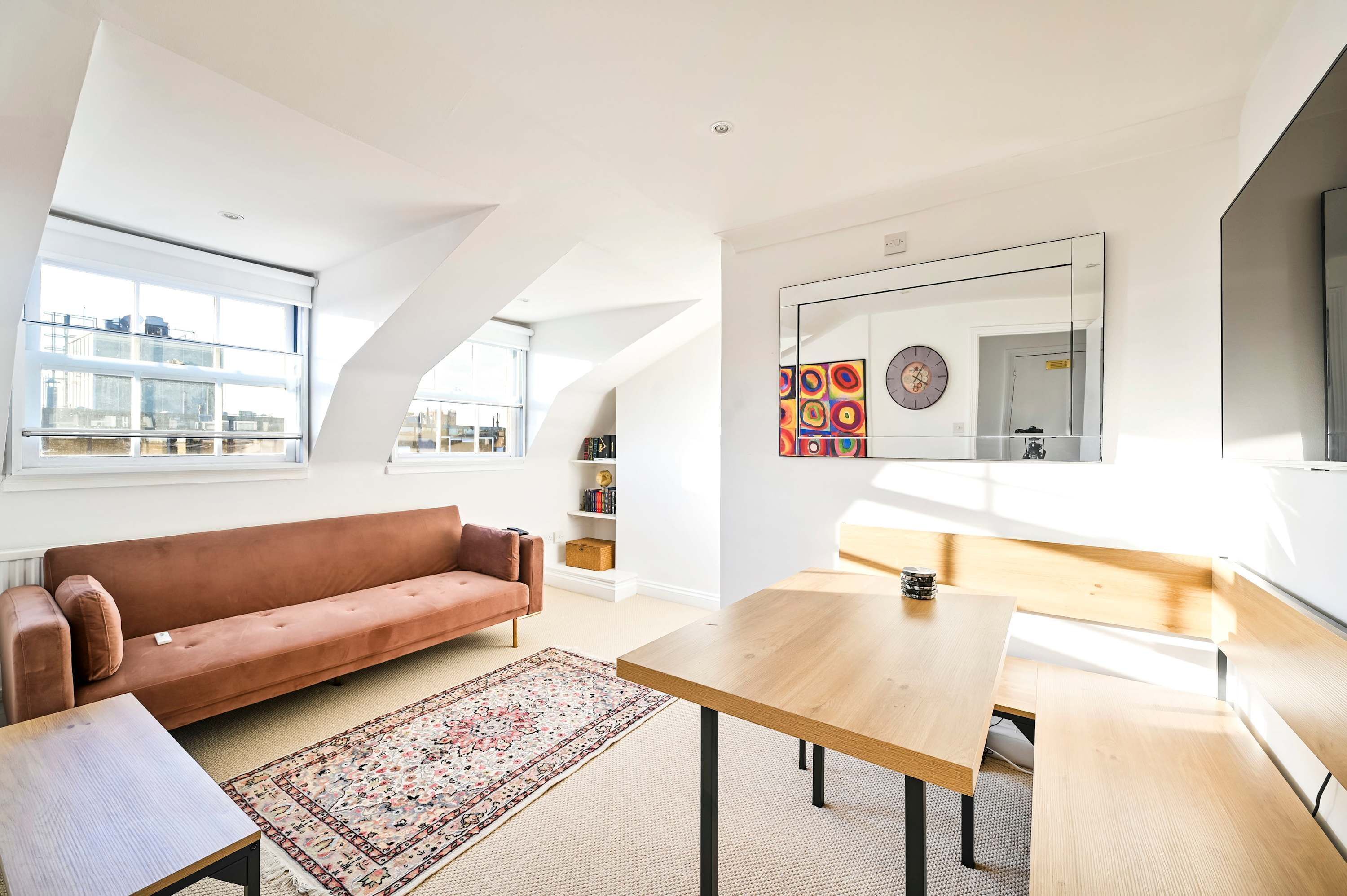 A modern living room with a sofa, a wooden table, a bench, and a large window.