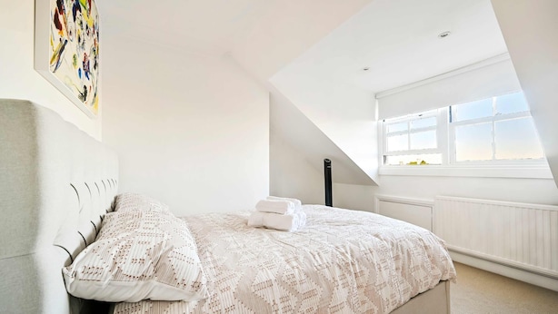 A bedroom with a bed, a window, and a painting on the wall. - Chelsea Loft - Stylish Sanctuary (London)