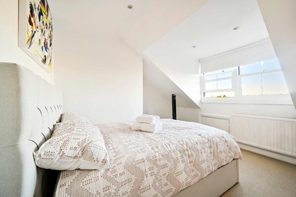 A bedroom with a bed, a window, and a painting on the wall. - Chelsea Loft - Stylish Sanctuary (London)
