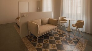 Una habitación con sofá, sillas, una mesita y piso con diseño.
