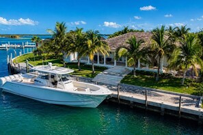 A boat docked at a marina with a white building and palm trees in the background.