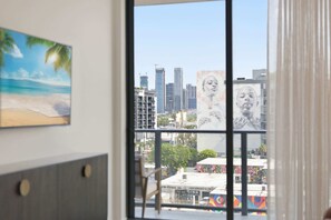 Ein Zimmer mit Blick auf eine Stadtlandschaft, ein Strandbild und ein großes Wandgemälde.