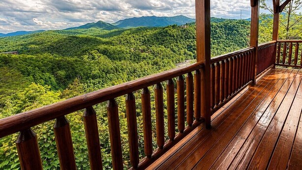 A wooden deck with a railing overlooking a lush green landscape. - Views Forever | Smoky Mountain Views, Hot Tub, Theater & Game Room (Gatlinburg)