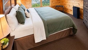 A wooden cabin bedroom with a bed, a ceiling fan, a window with a mountain view, and a dresser. - Views Forever | Smoky Mountain Views, Hot Tub, Theater & Game Room (Gatlinburg)