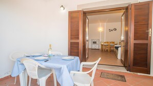 Un comedor con una mesa dispuesta para cuatro personas, sillas de plástico blanco y mantel azul.