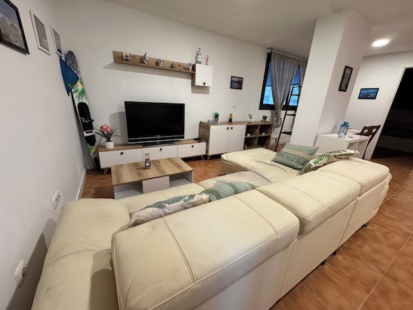 A living room with a sofa, TV, wooden coffee table, and a white cabinet.