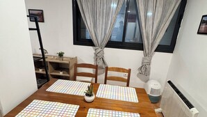 Un comedor con mesa de madera, cuatro sillas, una planta en maceta y un radiador.