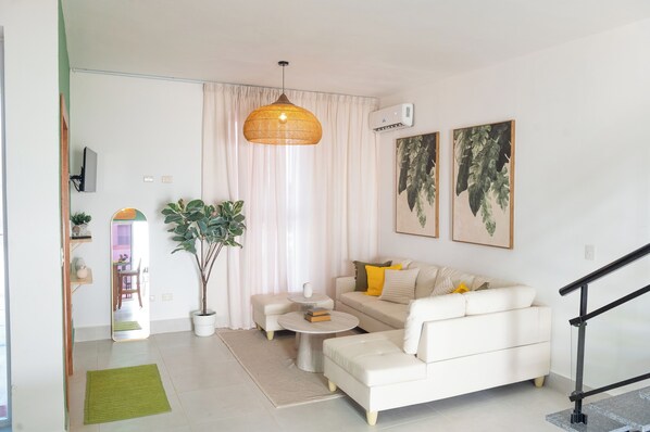 A modern living room with a sofa, coffee table, and a hanging light fixture.