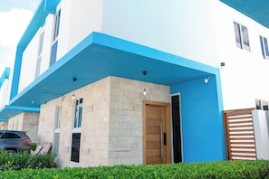 A modern building with a blue and white facade, a stone base, and a wooden door.