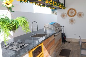 A kitchen with a gas stove, sink, and a built-in grill.