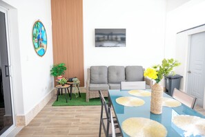 A dining area with a table, chairs, a sofa, a TV, and decorative items.