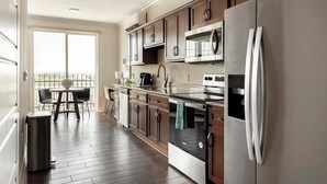 Una cocina moderna con armarios de madera oscura, electrodomésticos de acero inoxidable y un comedor con vista a un balcón.