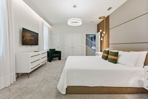 A modern bedroom with a large bed, a dresser, a chair, and a painting on the wall. - Unique Luxury Villa, Pool, Games and Themed Beds (Clermont)