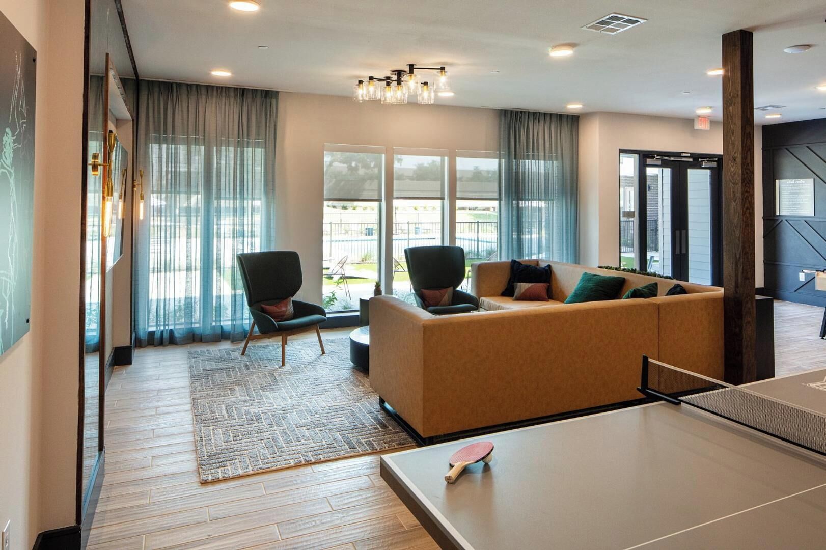 A modern hotel lobby with a sofa, chairs, a ping pong table, and large windows.