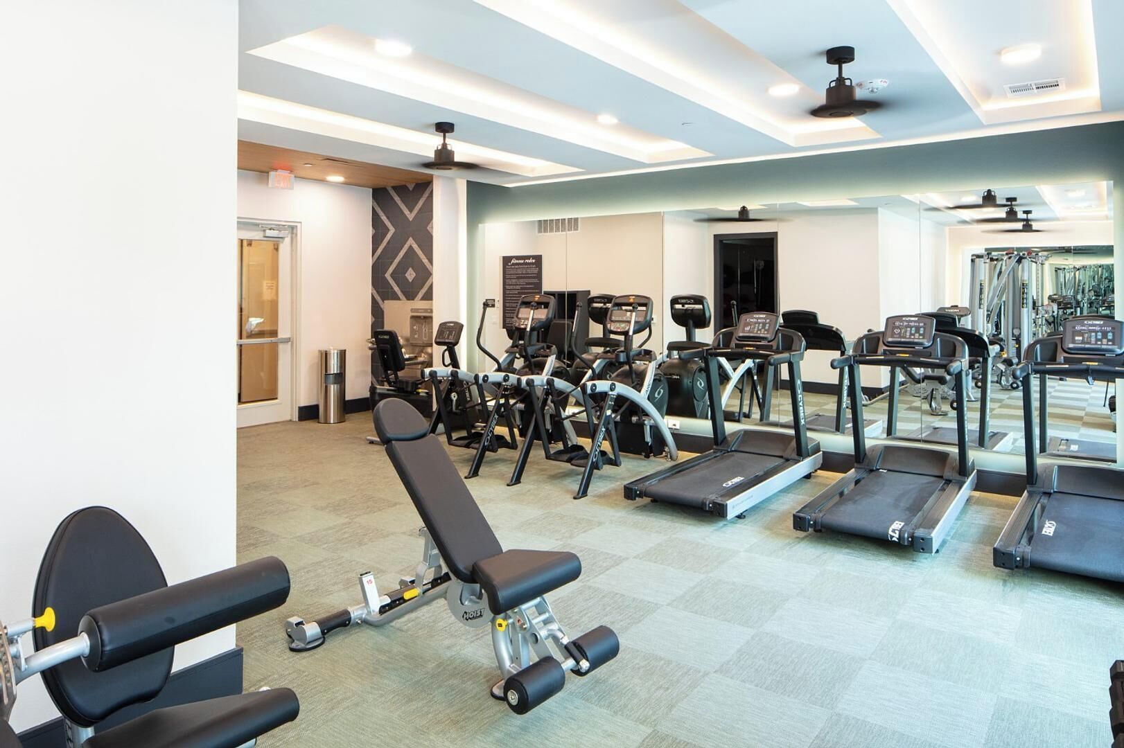 Ein Fitnessraum mit unterschiedlichen Trainingsgeräten, darunter Laufbänder, Ergometer und Kraftgeräte.