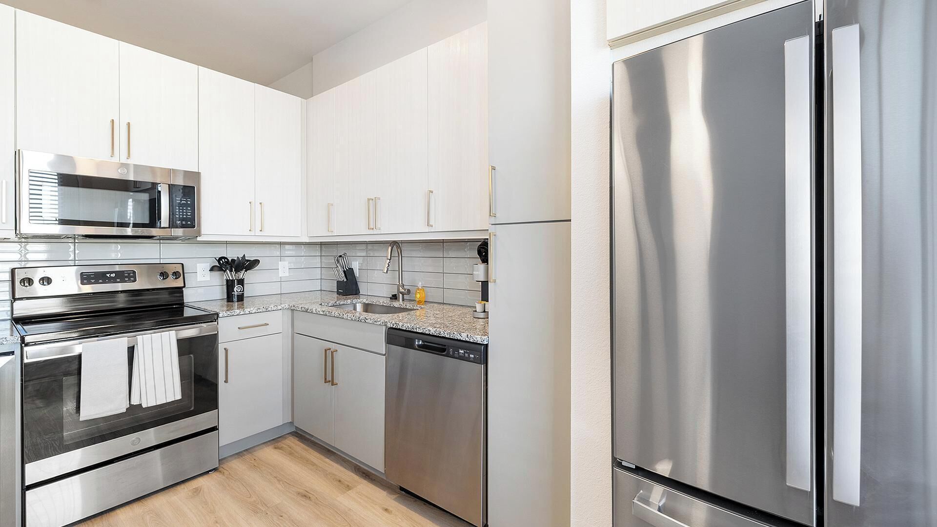 A modern kitchen with stainless steel appliances, white cabinetry, and a dishwasher.