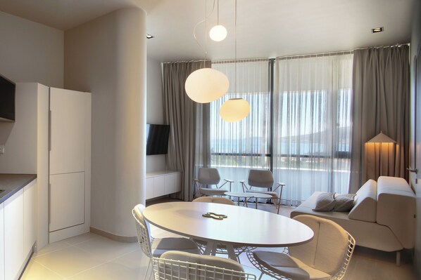 Une chambre d’hôtel moderne dotée d’un coin repas, d’un canapé et d’une télévision.
