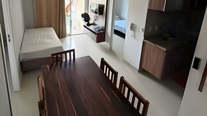 Un ambiente compatto con tavolo da pranzo, angolo cottura, letto e bagno.