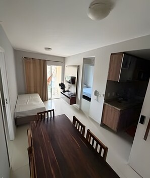 A compact living space with a dining table, a kitchenette, a bed, and a bathroom. - VG Fun Residence - Praia do Futuro (Fortaleza)