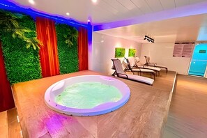 A spa room with a circular hot tub, wooden flooring, and a green wall with curtains. - VG Fun Residence - Praia do Futuro (Fortaleza)