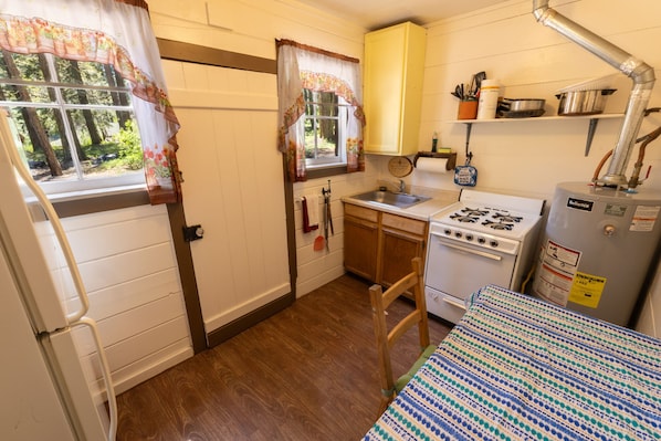 A compact kitchen with a stove, sink, and wooden cabinets.