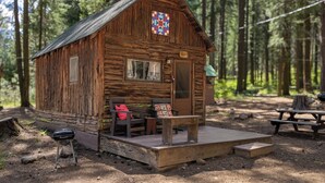 Un chalet rustique doté d’une véranda, d’un banc et d’une table de pique-nique.