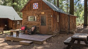 Une cabane rustique dotée d’une véranda, d’une porte et d’une fenêtre.