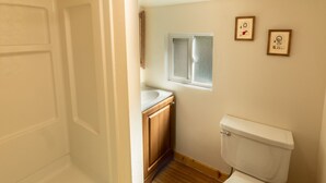 Une petite salle de bain avec des toilettes, une fenêtre et des meubles en bois.