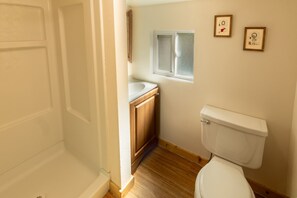 Ein kleines Badezimmer mit Toilette, Fenster und Holzschränken.