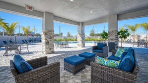 Ein Terrassenbereich im Freien mit Korbmöbeln, einem Pool und blauem Himmel.
