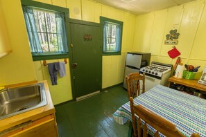 A compact kitchen with a sink, stove, refrigerator, and wooden table.