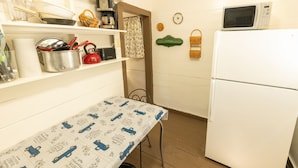 A kitchen with a table, a refrigerator, and various kitchen items on shelves.