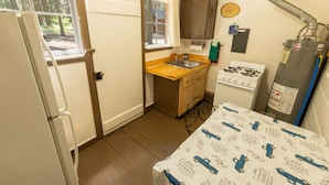 A compact kitchen with a sink, stove, and a table with a patterned tablecloth.