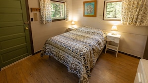 A bedroom with a bed, two bedside tables, a window, and a door.