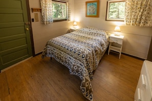A bedroom with a bed, two bedside tables, a window, and a door.