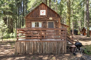 A rustic cabin with a wooden deck, a front door, and a small porch.