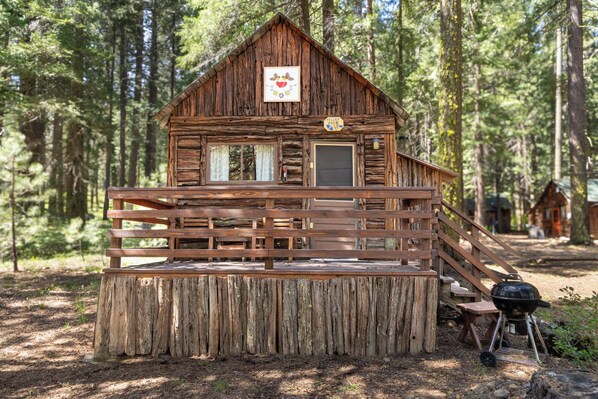 A rustic cabin with a wooden deck, a front door, and a small porch.