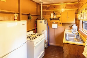 Een kleine keuken met een fornuis, koelkast en spoelbak.