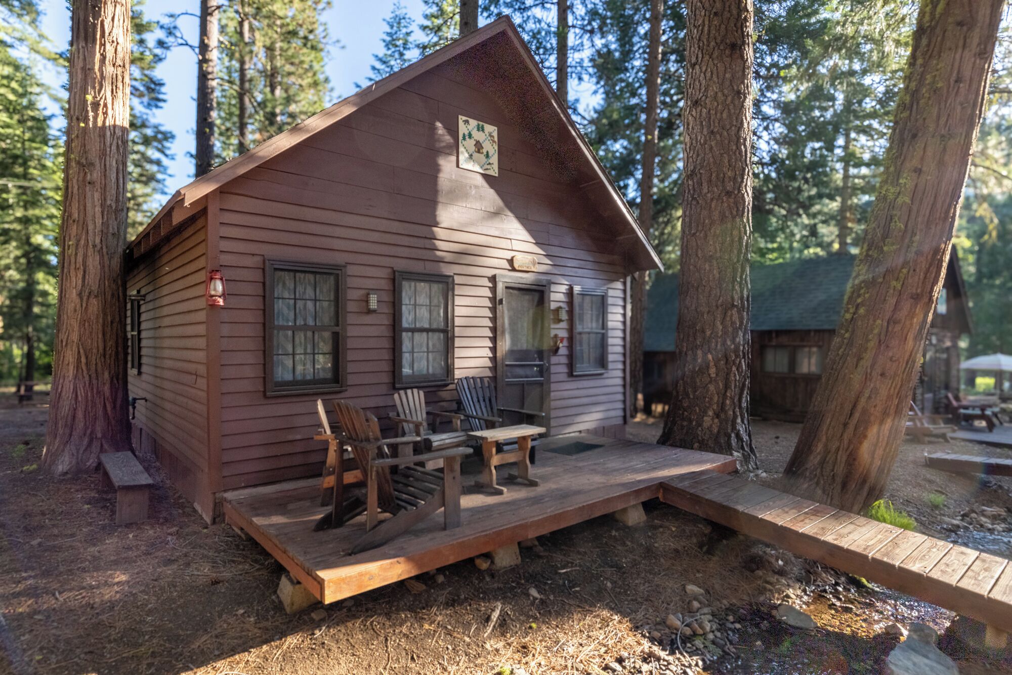 A cabin with a porch, wooden chairs, a table, and a small deck.
