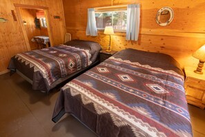 Une chambre de style cabane avec deux lits, une fenêtre avec des rideaux, une lampe et un mur en bois.