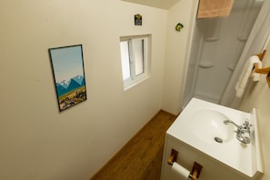 Een badkamer met een wastafel, een raam en een lijst met een foto aan de muur.