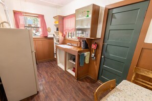 A compact kitchen with a refrigerator, wooden cabinets, a sink, and a dining area with a table.