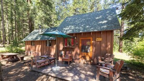 A wooden cabin with a porch, outdoor seating, and a sign reading 'Eagle's Nest.'